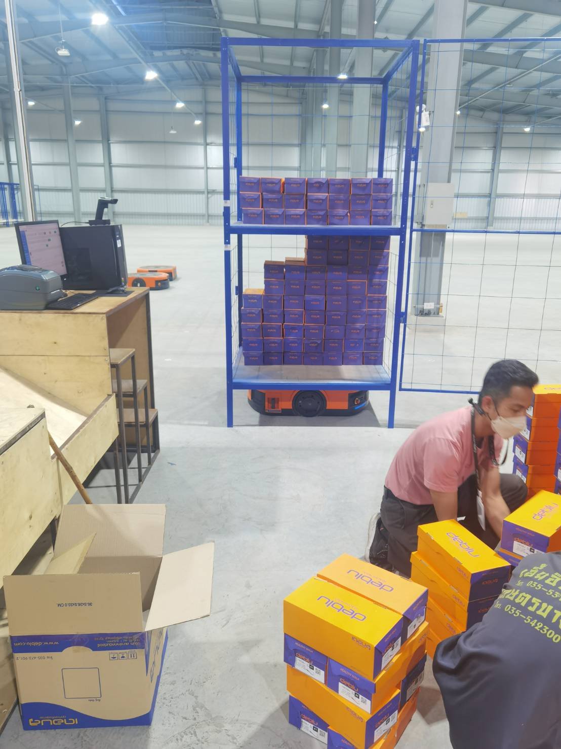 Picker selecting from the rack the AGV delivered — no walking required.